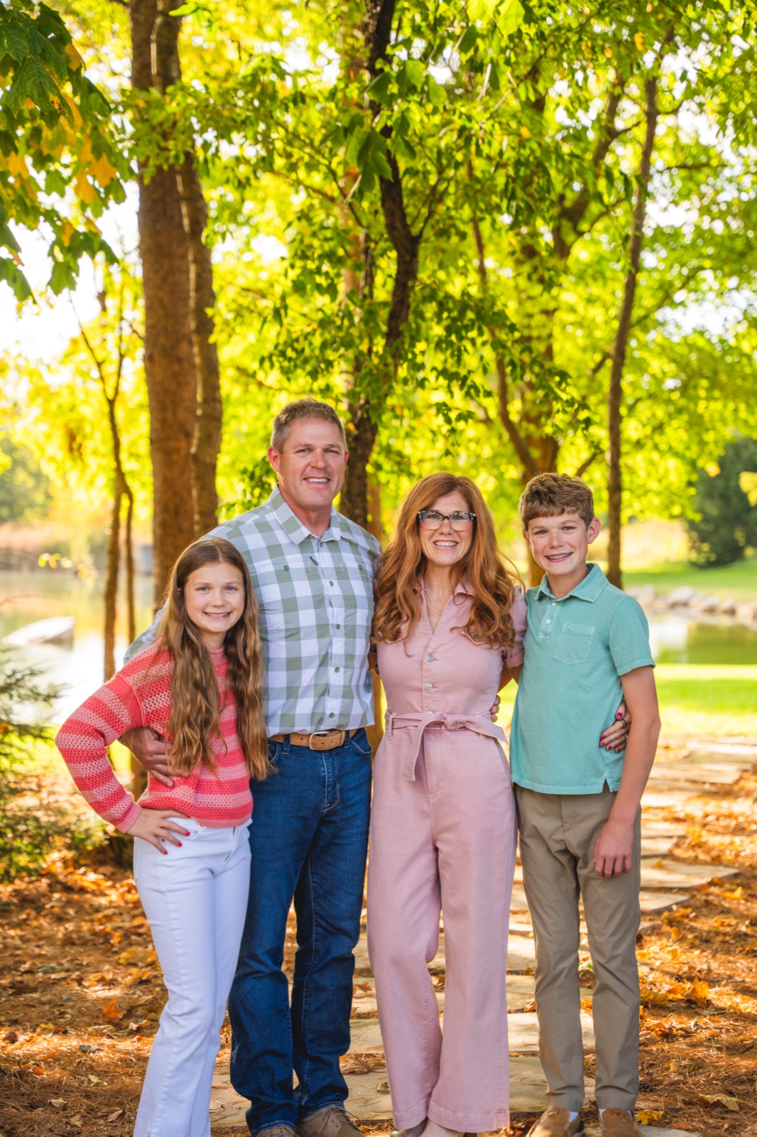 Sara, her husband, and their two kids together among autumn trees.