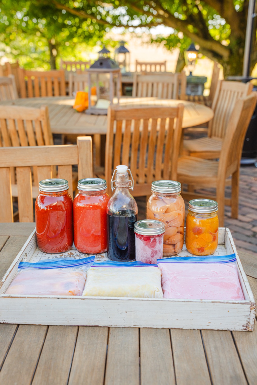 Canned goods in glass jars and frozen bags arranged on a tray.