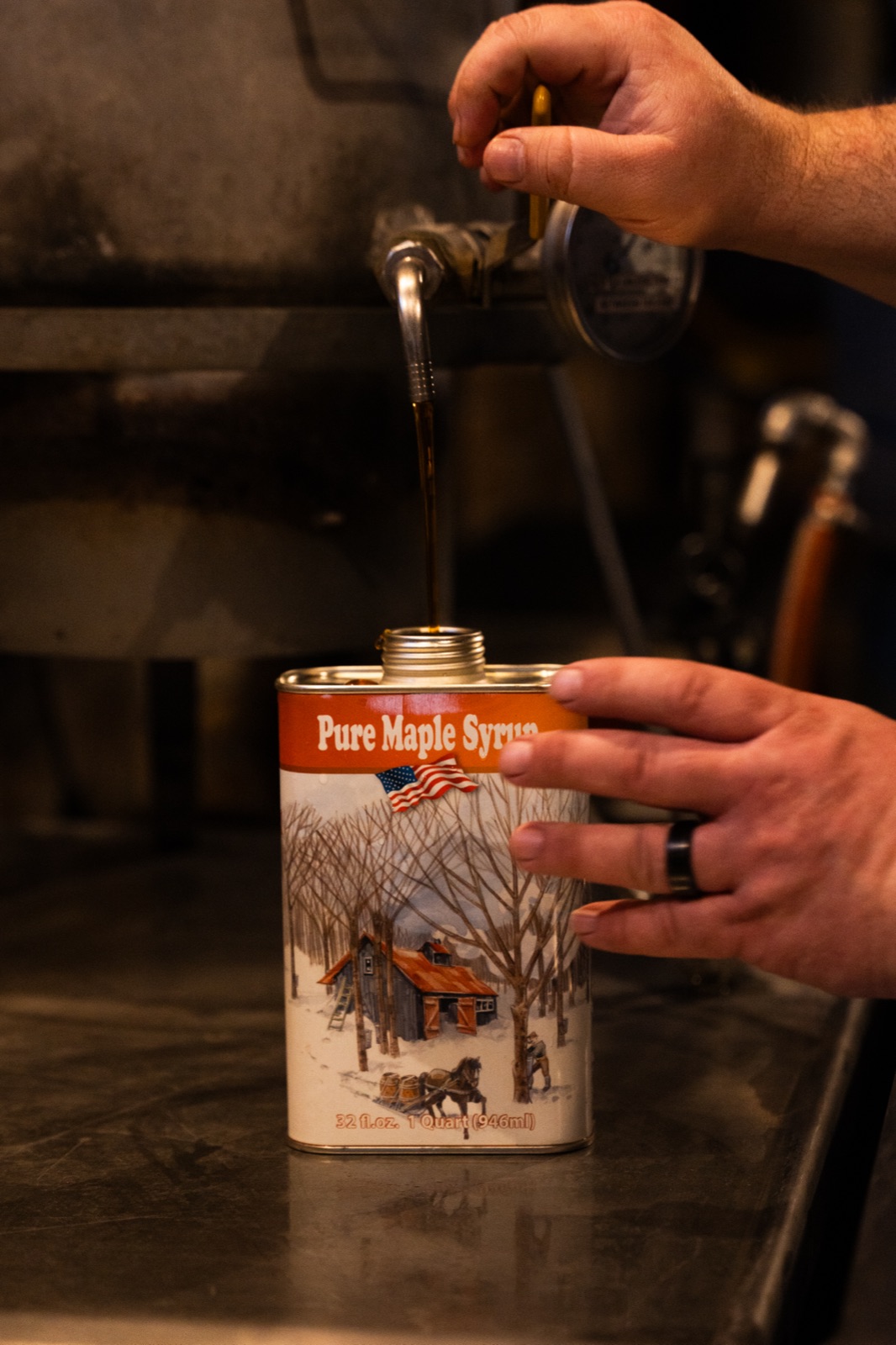 Hot maple syrup being poured into a metal syrup can.